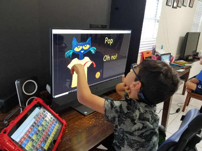 A boy points to the buttons on Pete the Cat's shirt