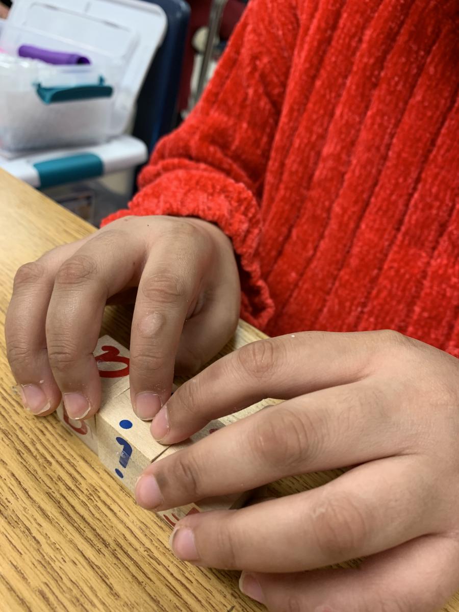 Student reading the braille labels on wooden blocks Student reading the braille labels on wooden blocks