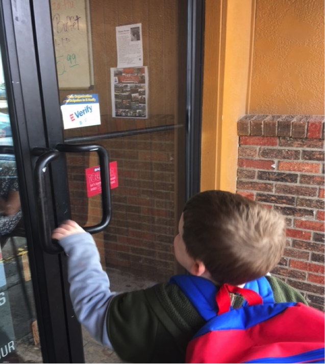 A boy opens the door to the pizza restaurant