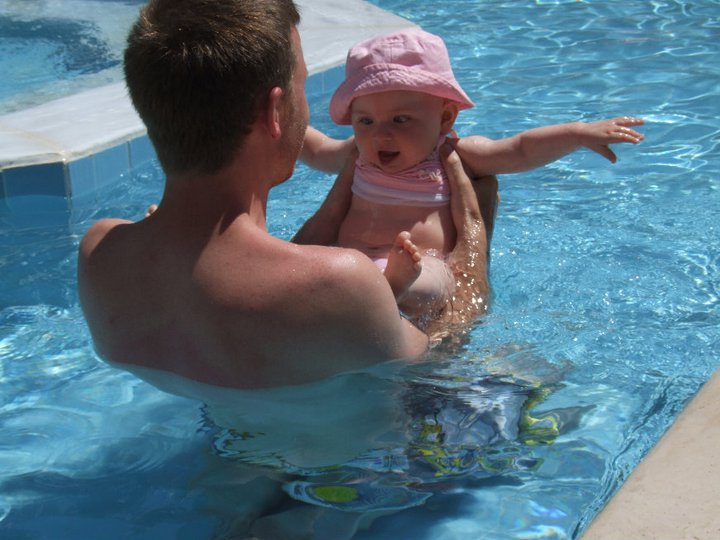 man holds baby in pool