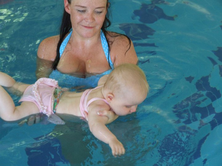 woman holds baby in pool