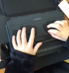 D begins to write her response on her braillewriter