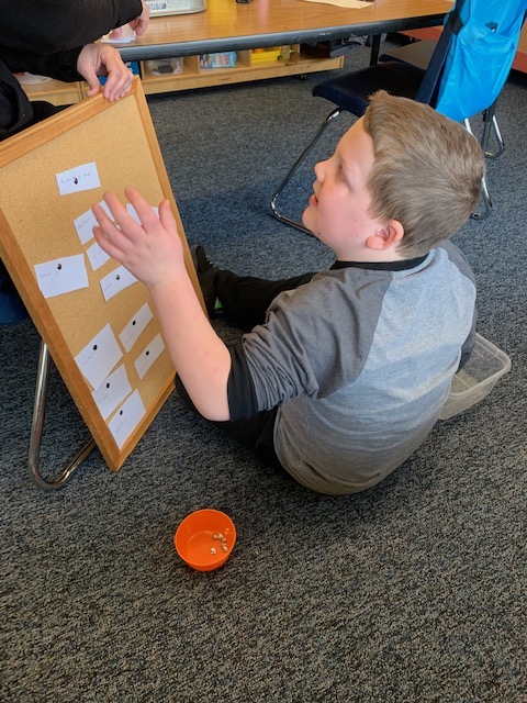 Boy reaching up to place word card on bulletin board