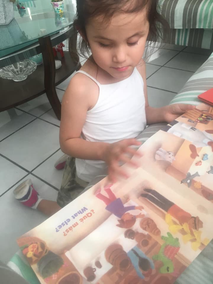 A young girl examines a book in English and Spanish.