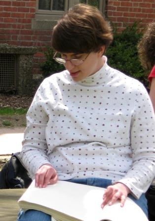 A girl reads braille outside