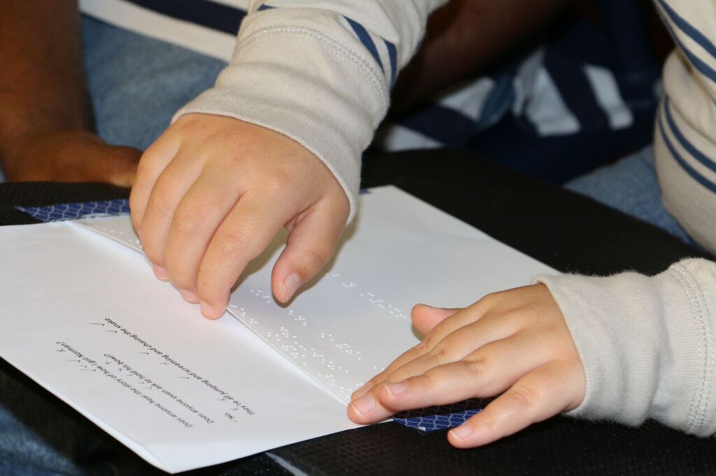 Student reading braille paper