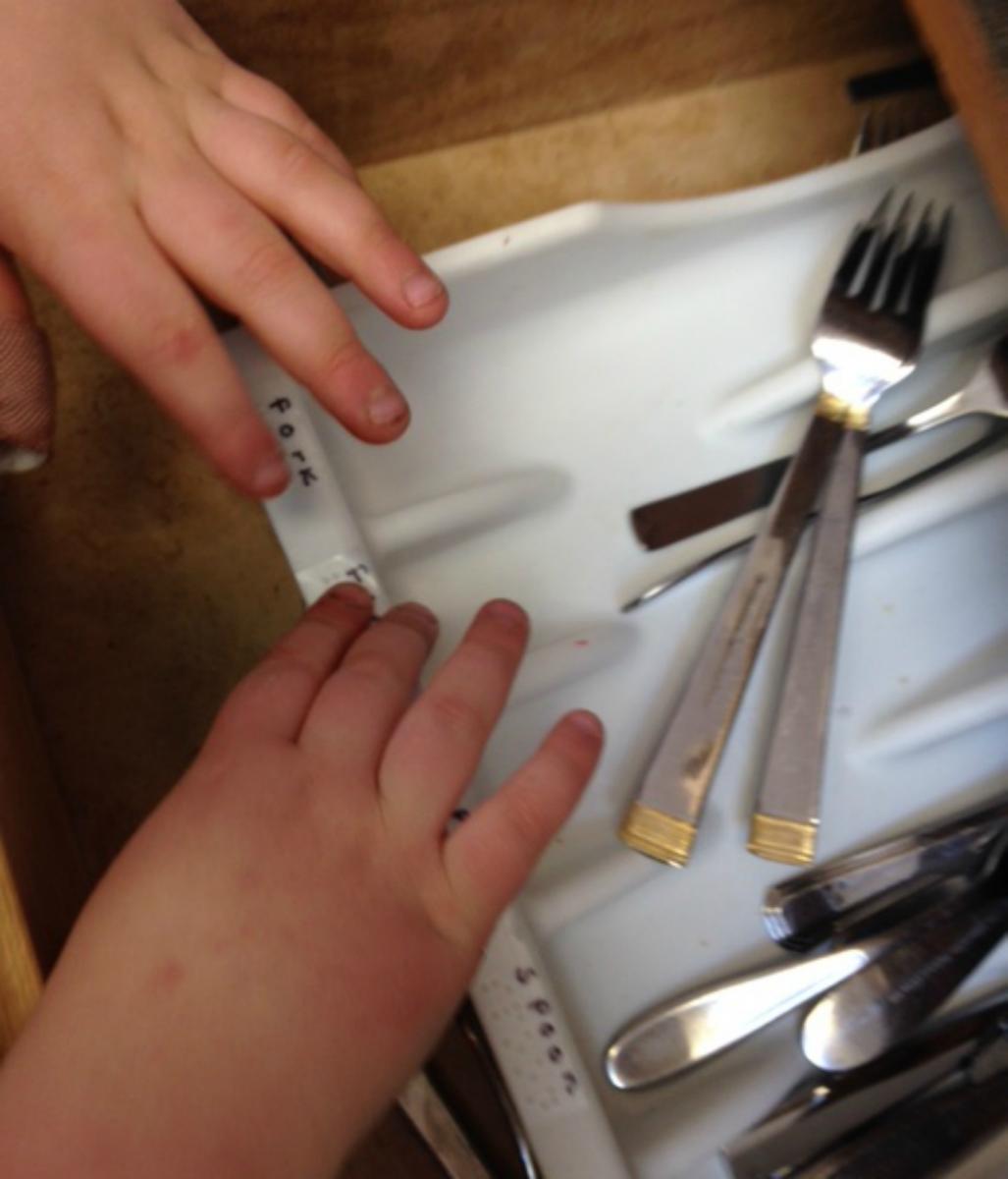 Child reading braille labels on silverware sorter