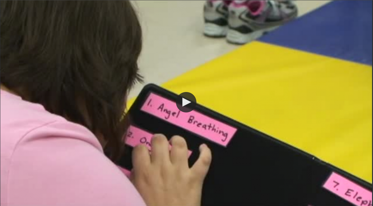 A yoga student with a visual impairment reads the routine cards in print.