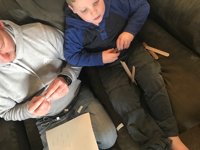 Liam reading the sticks. Liam sitting on a couch, reading the sticks