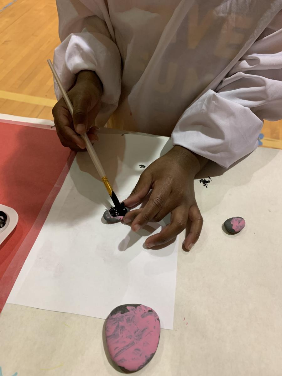 A student holds a rock as he paints it.