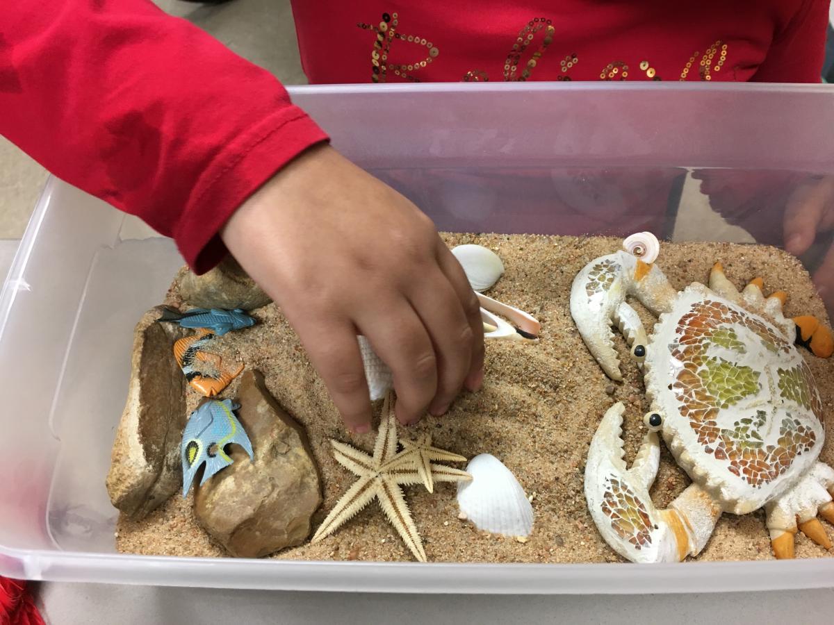 A child exploring the sand tray