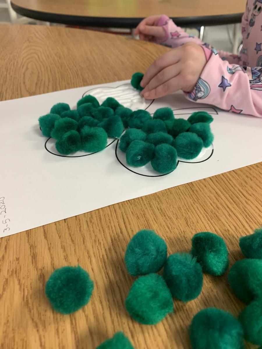 Placing green pompoms on glue