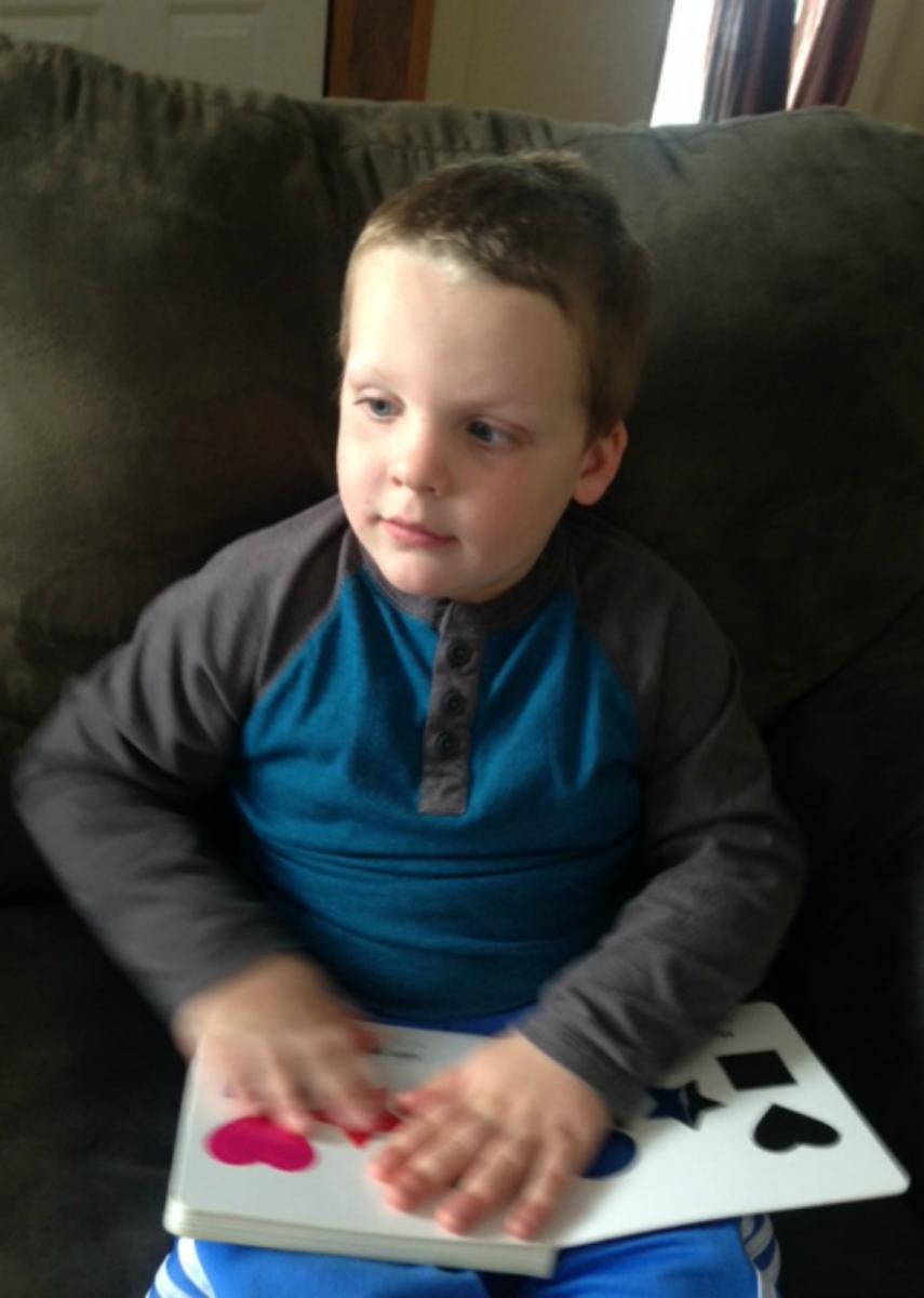 A young boy reads the shape book.