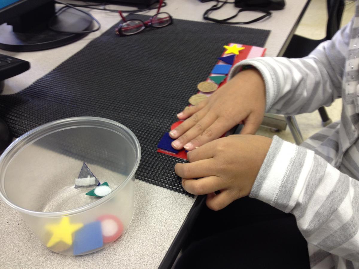 Student creating pattern with shapes on velcro strip