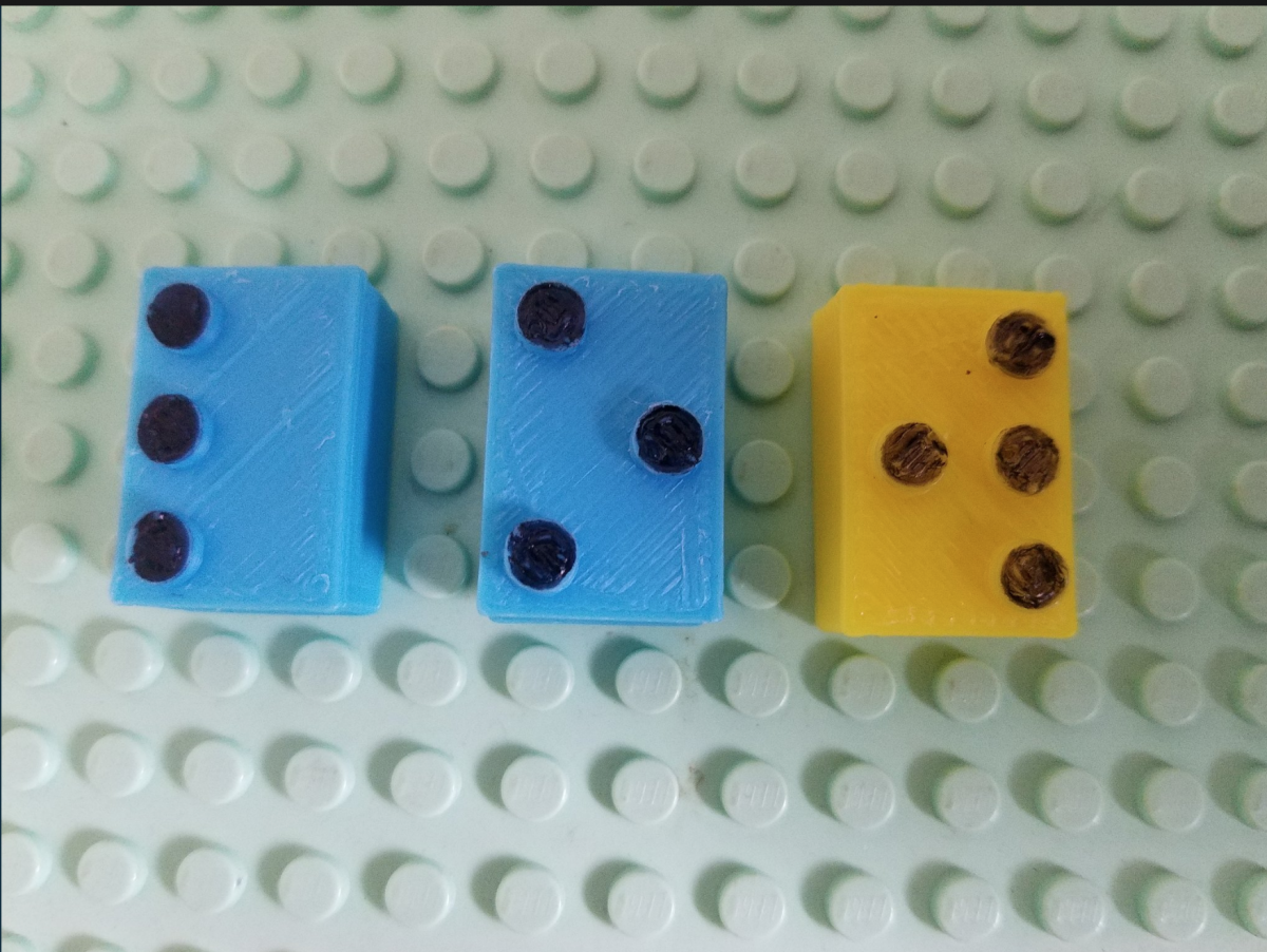 3 Lego alphabet bricks spell out the word “low” on a Lego base 3D braille legos spelling "low"