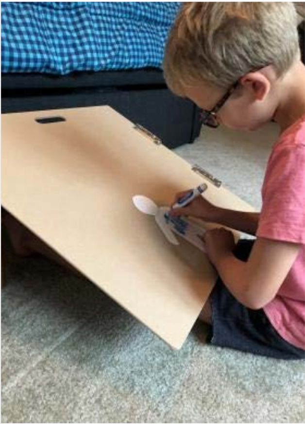 A boy coloring on a slant board