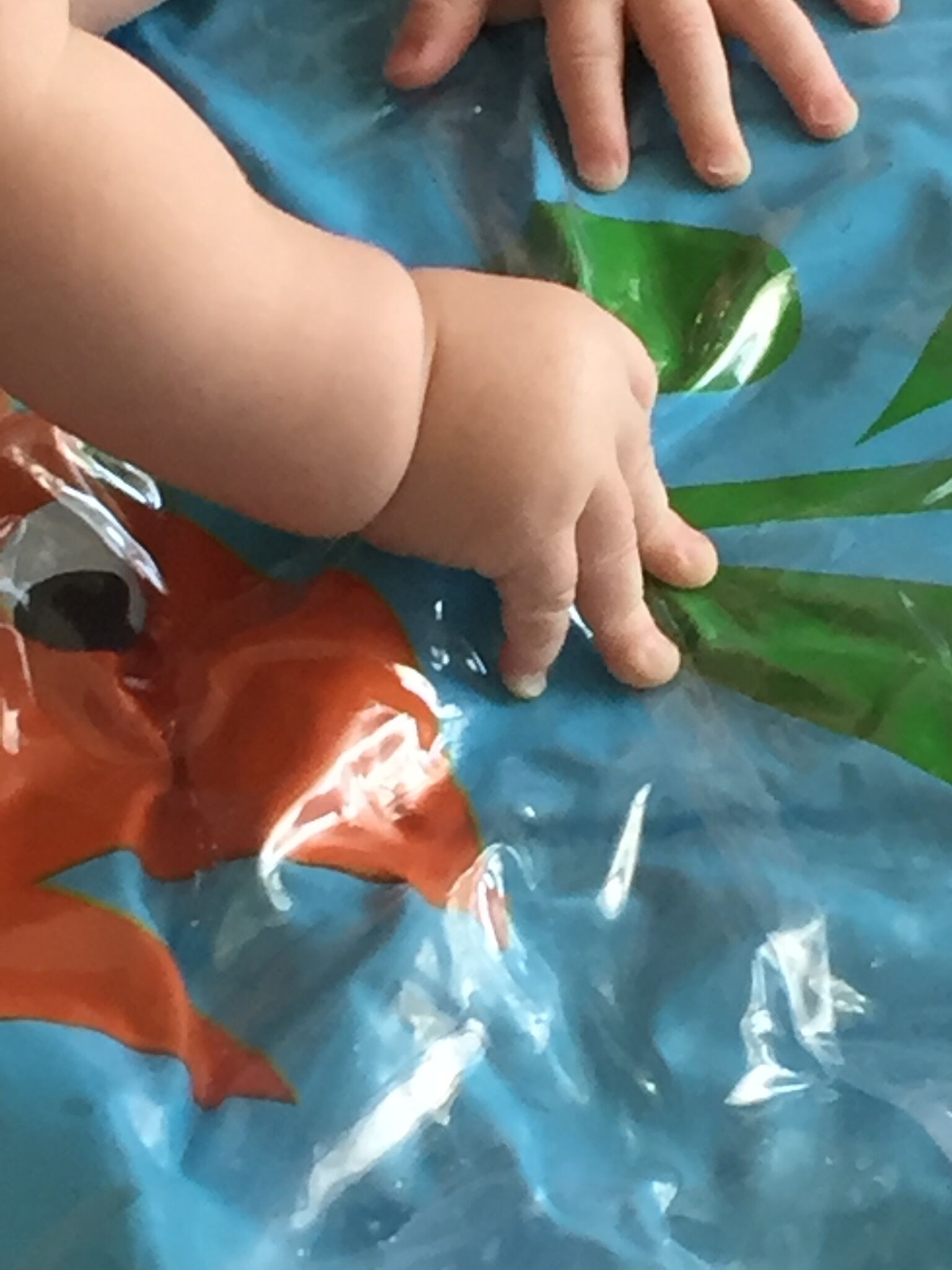 A baby's hands explore a splashpad