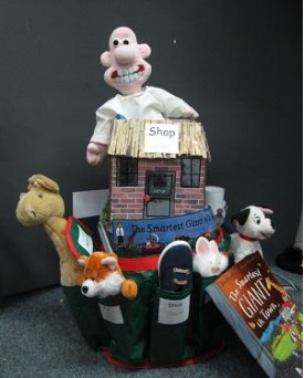 a bucket containing a doll, plush animals, and a toy cottage