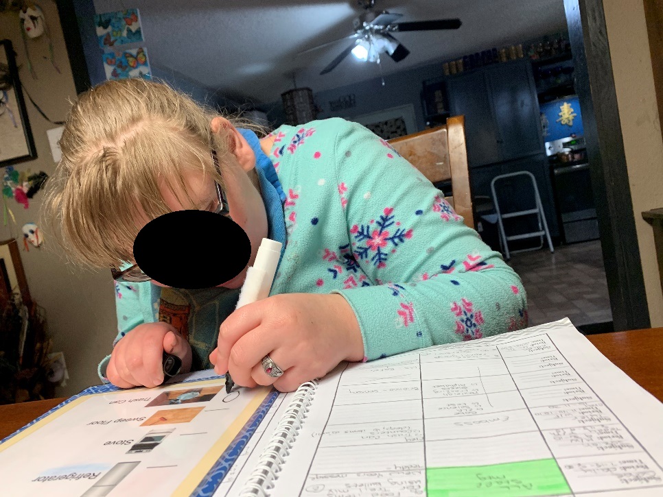 Adolescent student with glasses writing in a planner