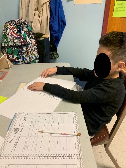 5th grader reading a bound volume of braille