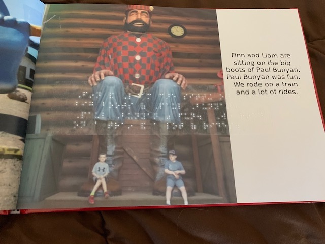 Page from photo book with picture of two boys in front of Paul Bunyan statue