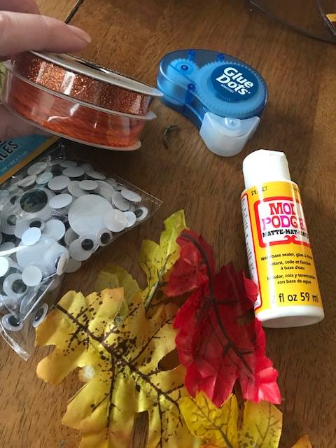 supplies for the project including leaves, modge-podge glue, glue dots, and ribbon