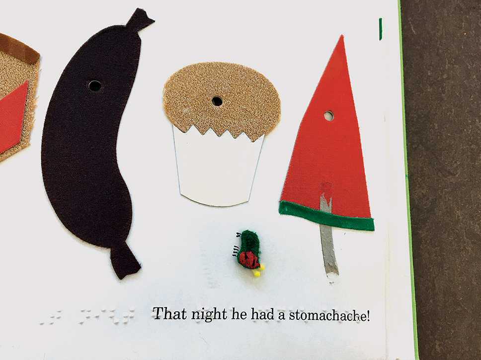 Picture of a book with tactile images of a sausage, muffin, watermelon, and the caterpillar. “That night he had a stomachache” is written in Braille and print.