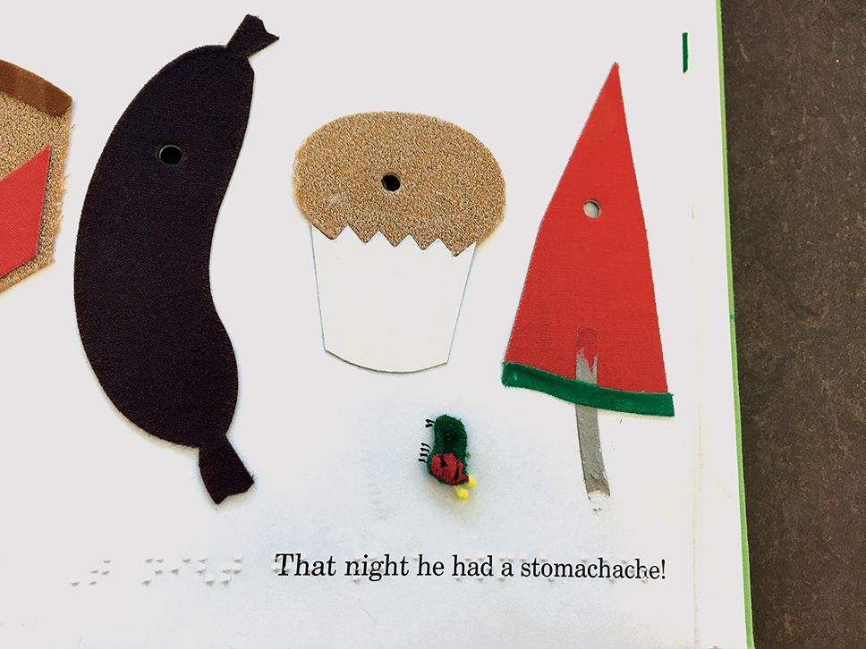 Tactile images in Picture of a book with tactile images of a sausage, muffin, watermelon, and the caterpillar. “That night he had a stomachache” is written in braille and print.