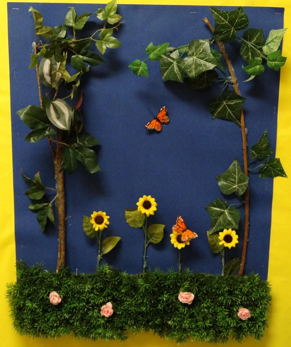tactile poster with leaves and yellow sunflowers and hedges with pink roses and an orange butterfly