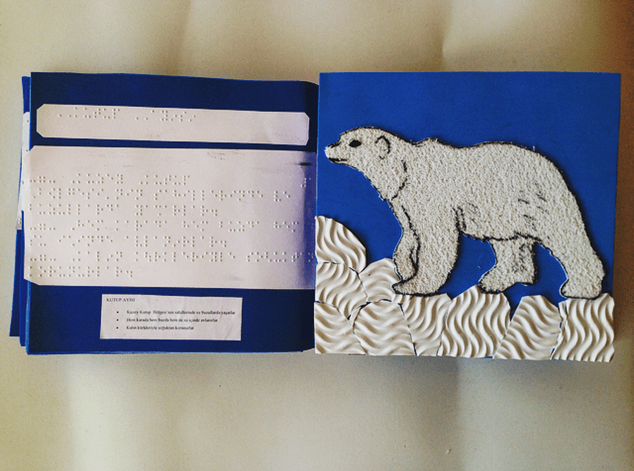 polar bear on snow made from differently textured items with a page of braille description facing it