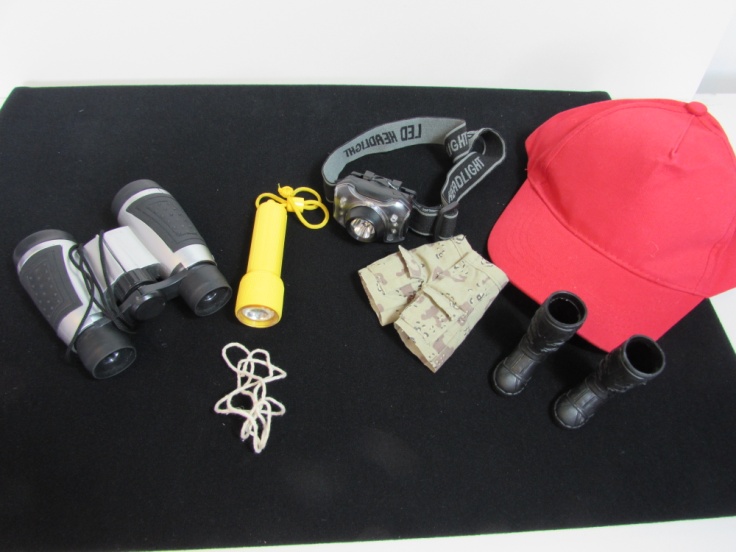 Traction Man's equipment including binoculars, rope, a head torch, a torch, and a hat