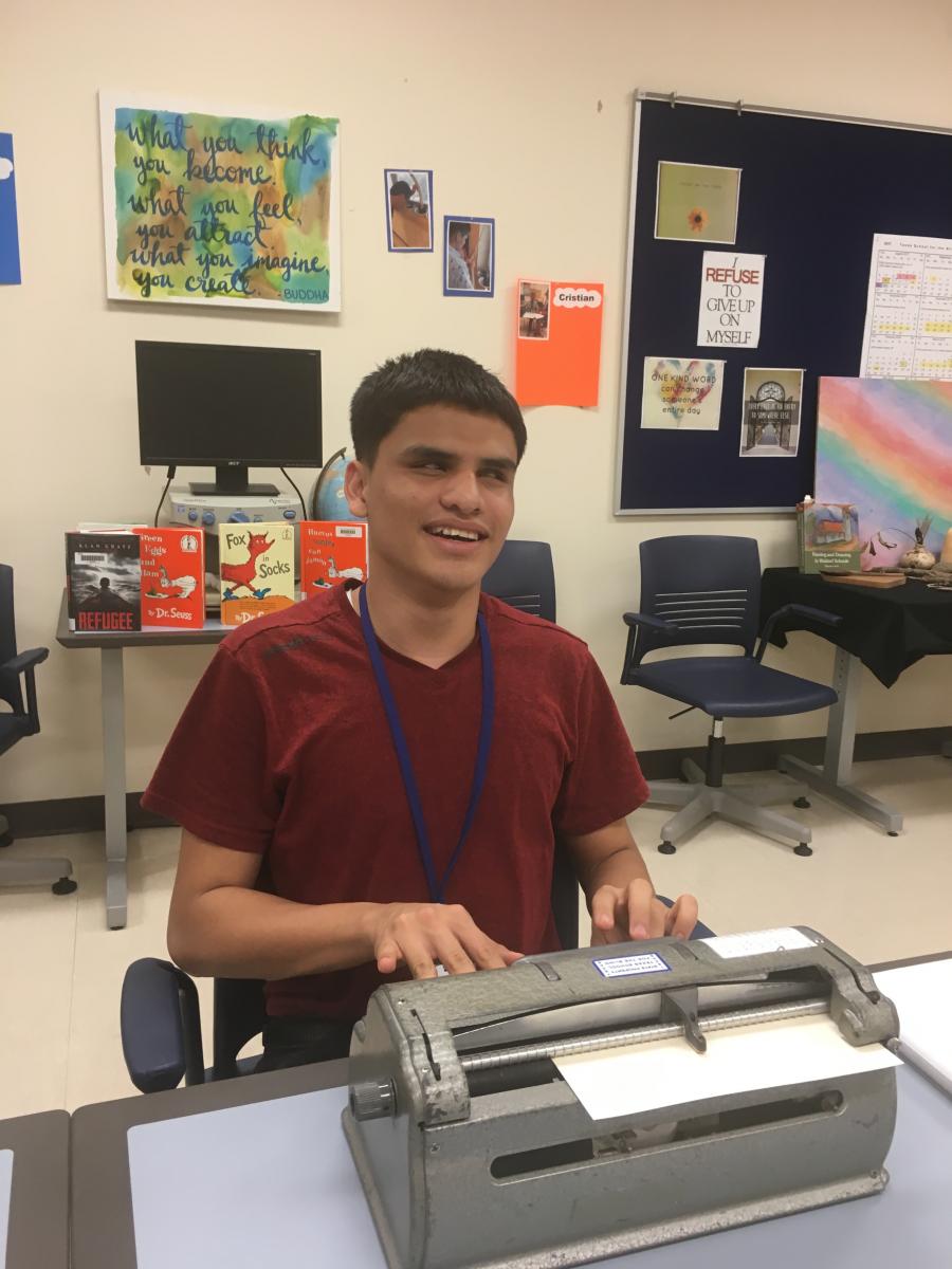 A teenage boy uses a braillewriter