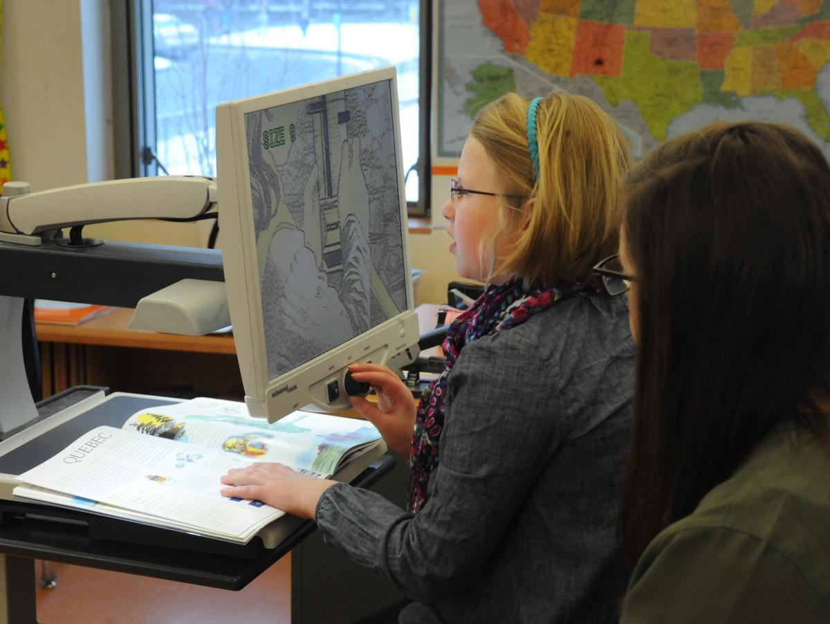 A student with low vision uses a video magnifier to look at a book.