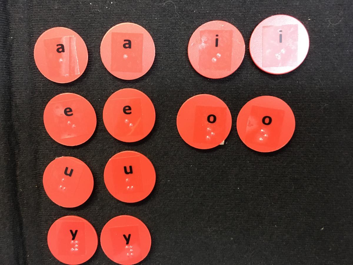 Vowels with print and braille on round circles