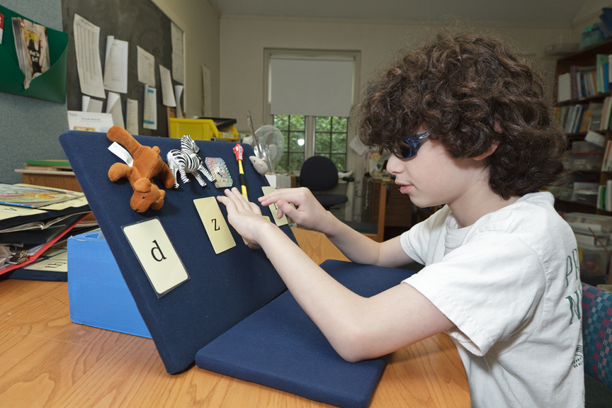 Student is using small objects to represent key words during the Sound Cards Quick Drill (part one of the 10-step lesson plan) Boy matches initial sound cards to corresponding objects