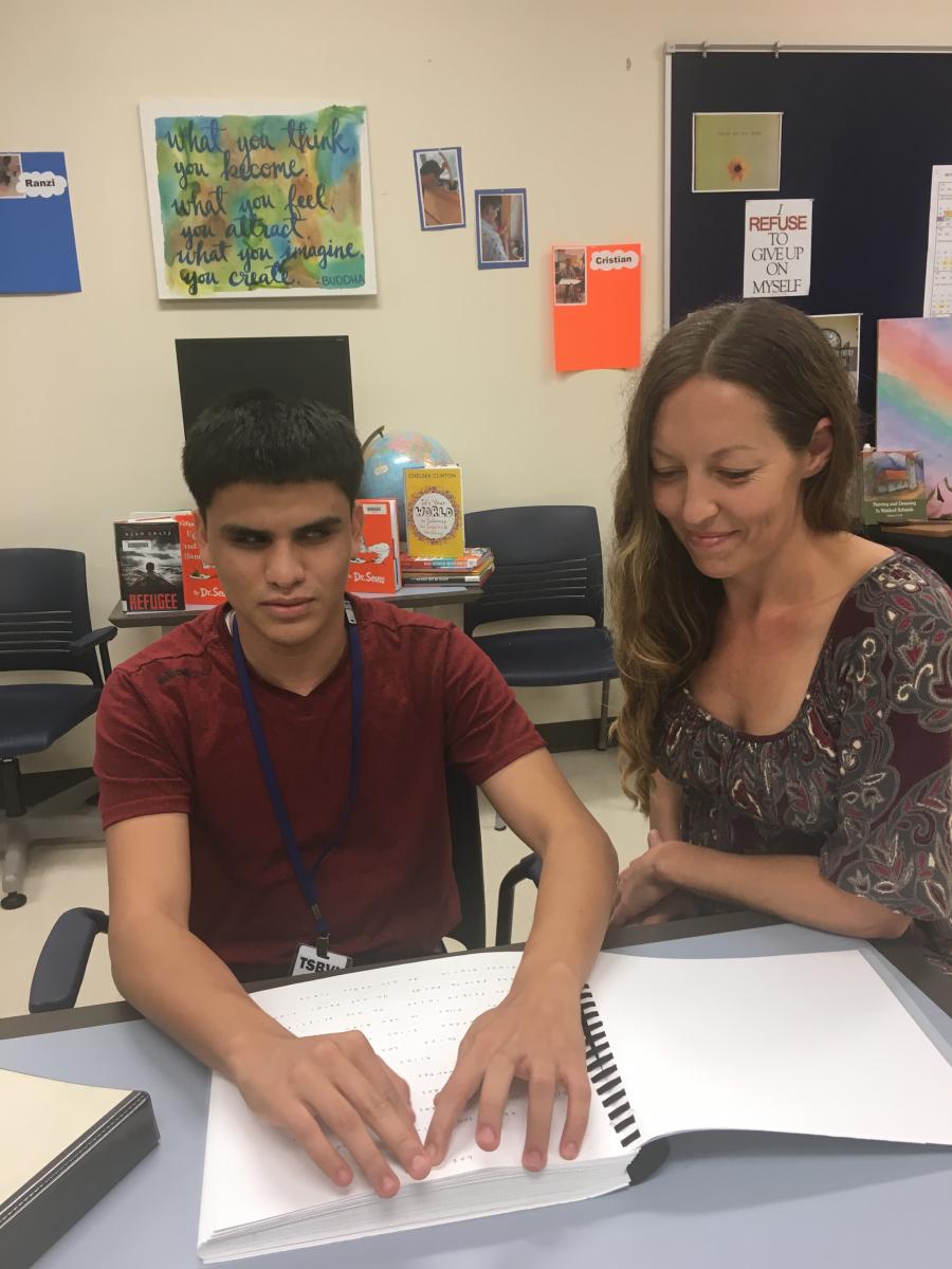 A teenage boy working with his teaching assistant