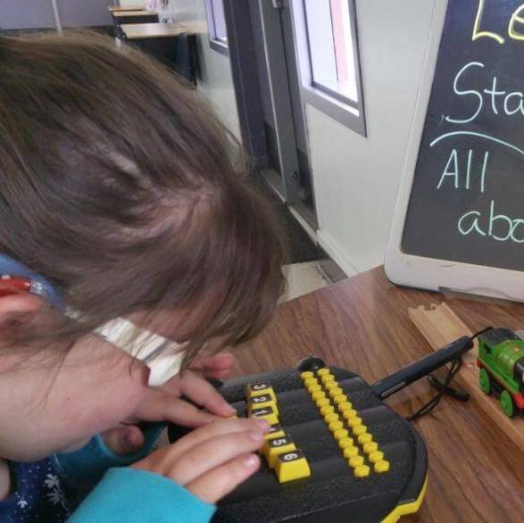 A girl uses an APH Braille Buzz with numbered keys.