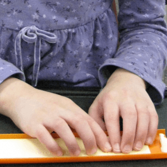 A child's hands reading a line of braille
