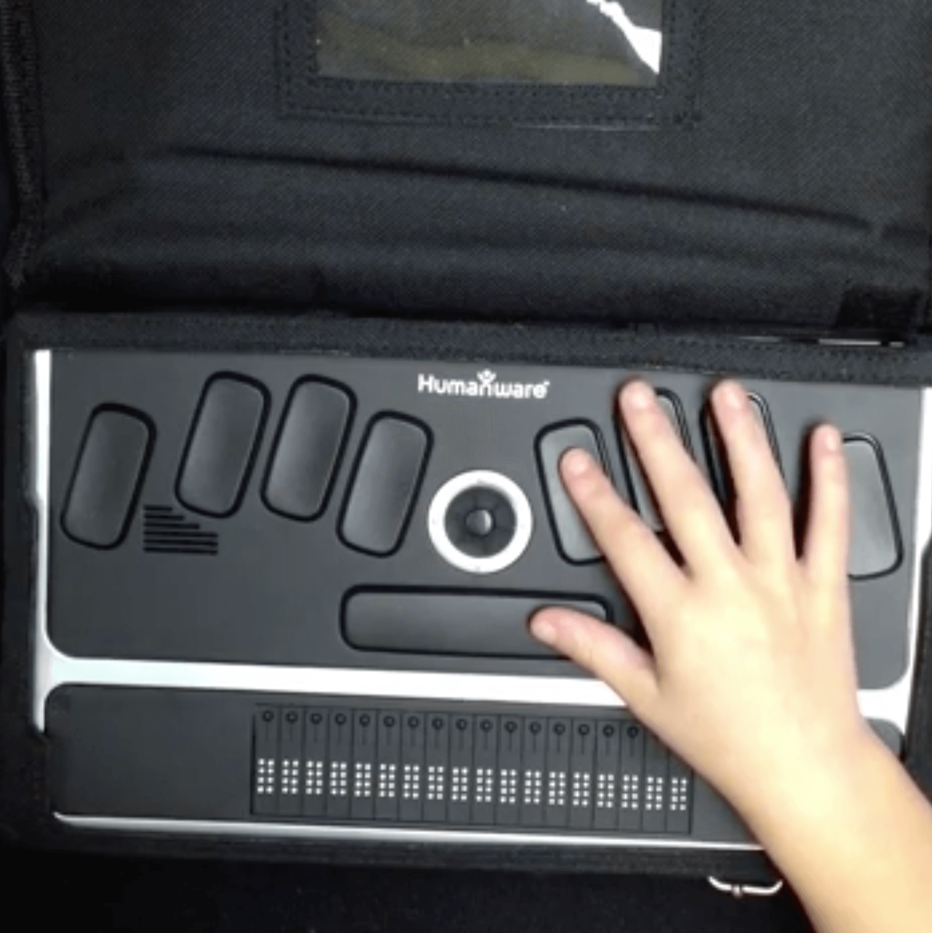 A young child with her right hand on the keys of a braillenote.