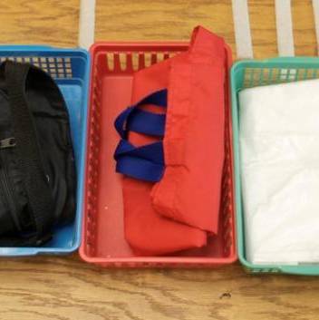 Real objects representing activities in the child’s day are arranged in left to right sequence in plastic bins.