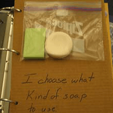 Page from an object book with two bars of soap in a baggie and the text “I choose what kind of soap to use.”