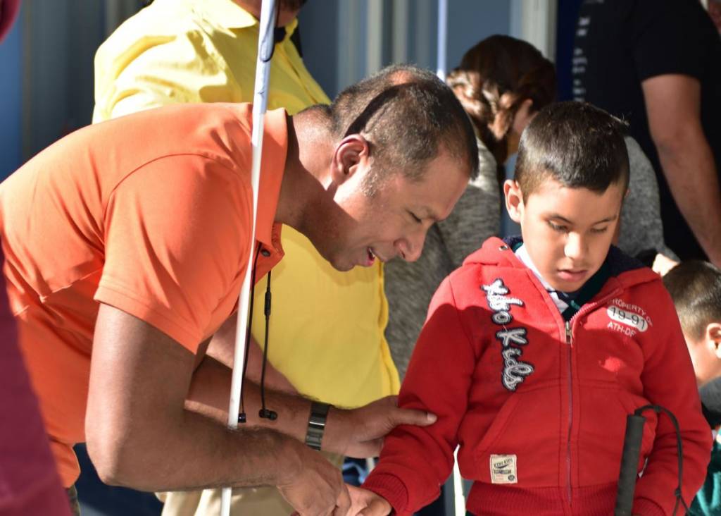 A man holding a long cane talks to a young boy who is also holding a long cane