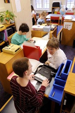 A teacher works individually with a student using a Braille Sense portable notetaker.