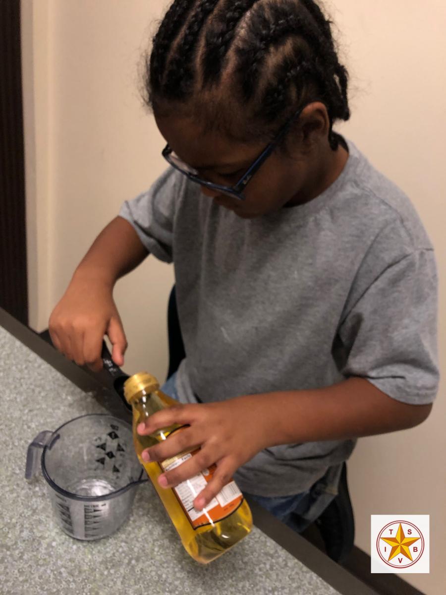 A child with glasses measures cooking oil