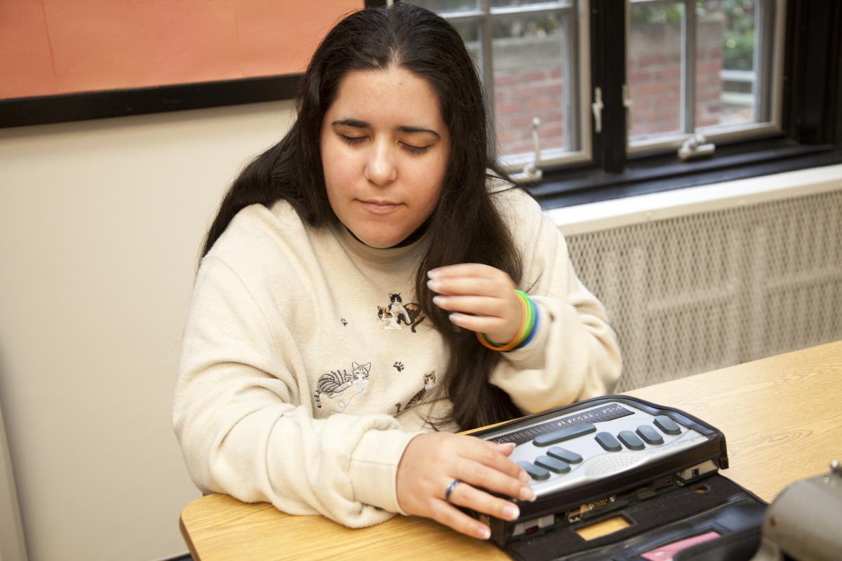 A girl uses her braille notetaker