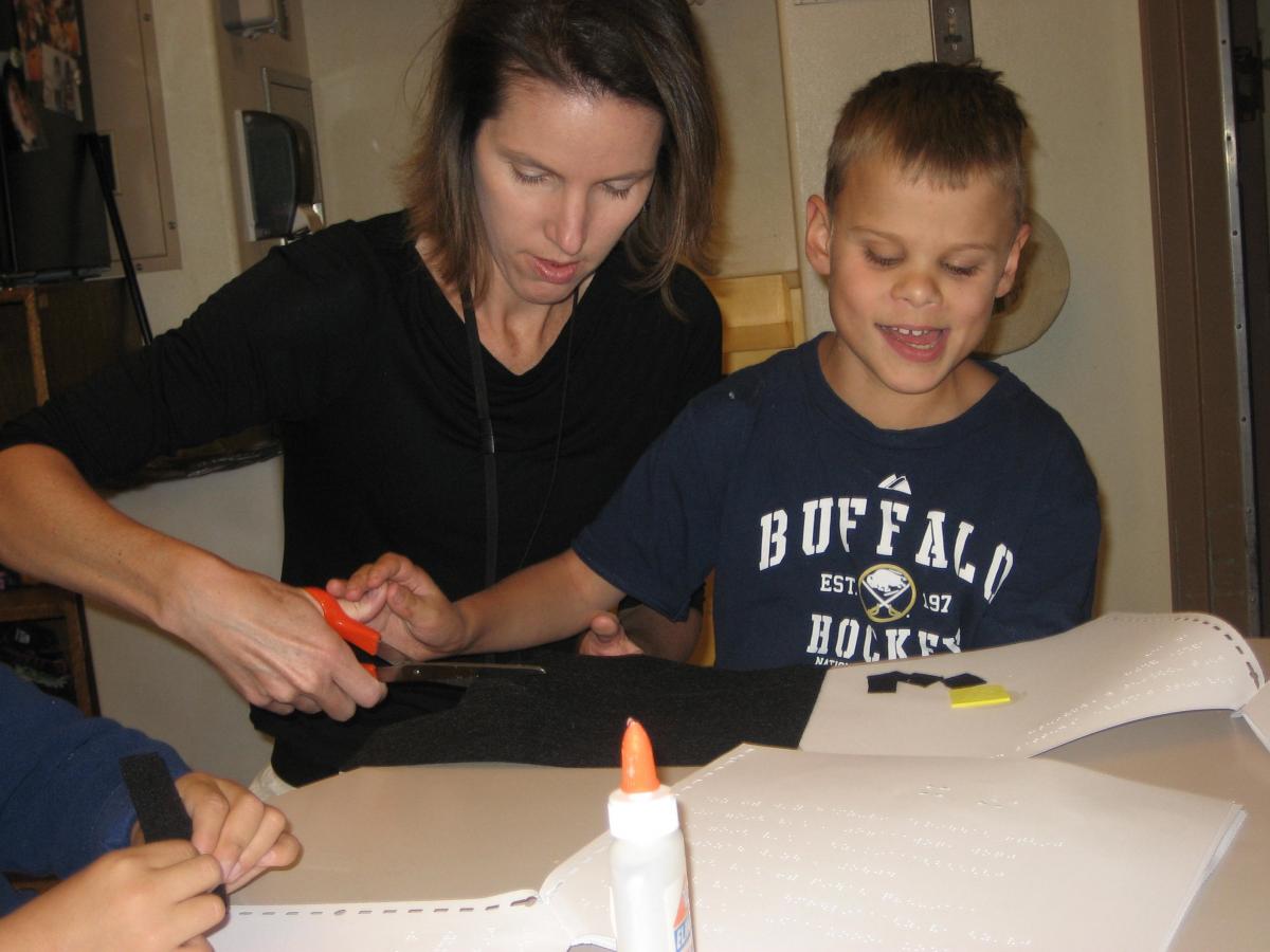 Image of teacher and boy working together to create a tactile book