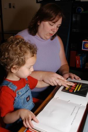 A young child and adult explore a tactile book together.
