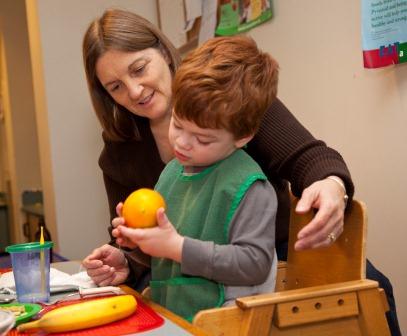 A boy and his teacher peel an orange.