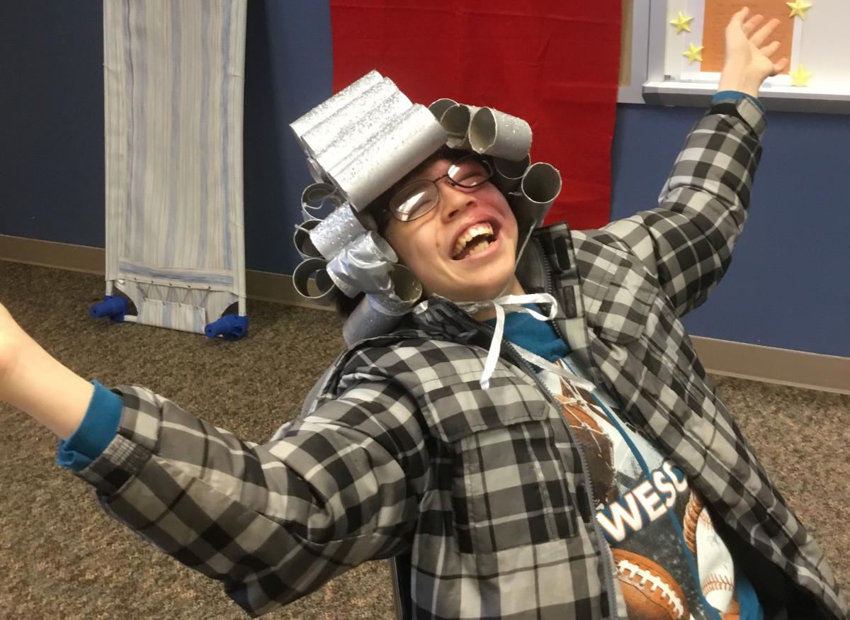 A boy with a wig made of toilet rolls.