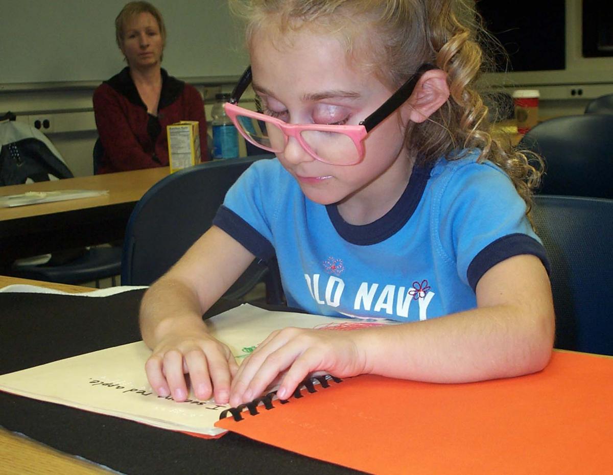 Haylee reading a homemade braille book
